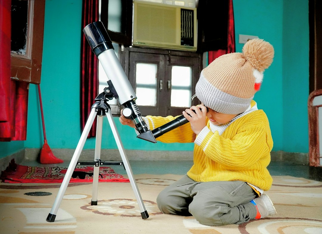 Niño observando a través de un telescopio, imagen de cabecera para una guía de libros infantiles sobre ciencia, experimentos y espacio