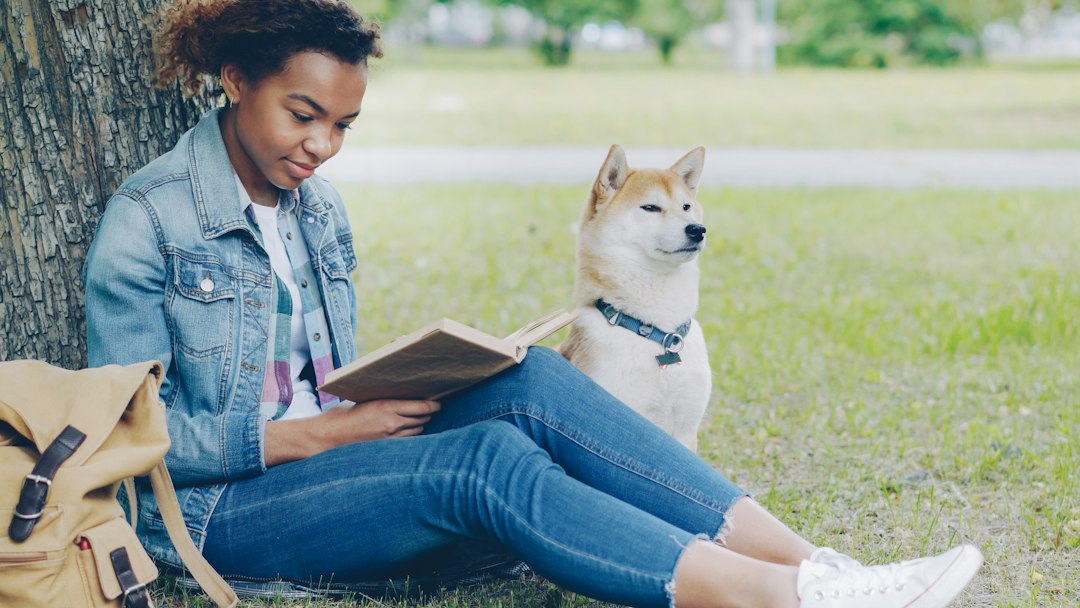 Niña leyendo al aire libre junto a un perro, imagen de cabecera para una guía de libros infantiles sobre animales