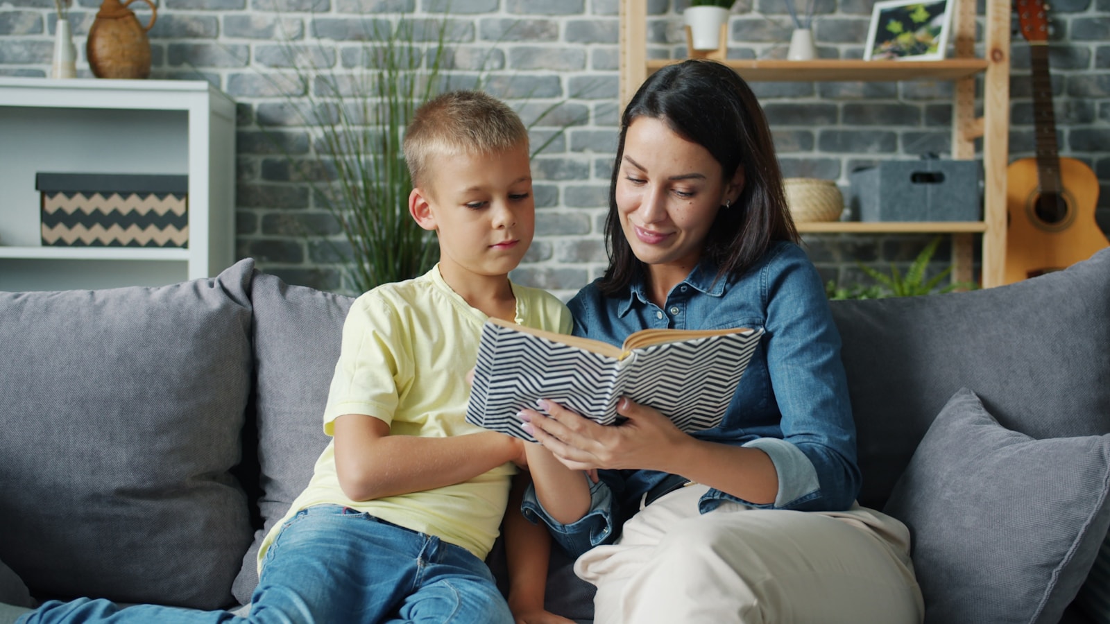 Niño leyendo un libro con un adulto y comentando juntos la historia