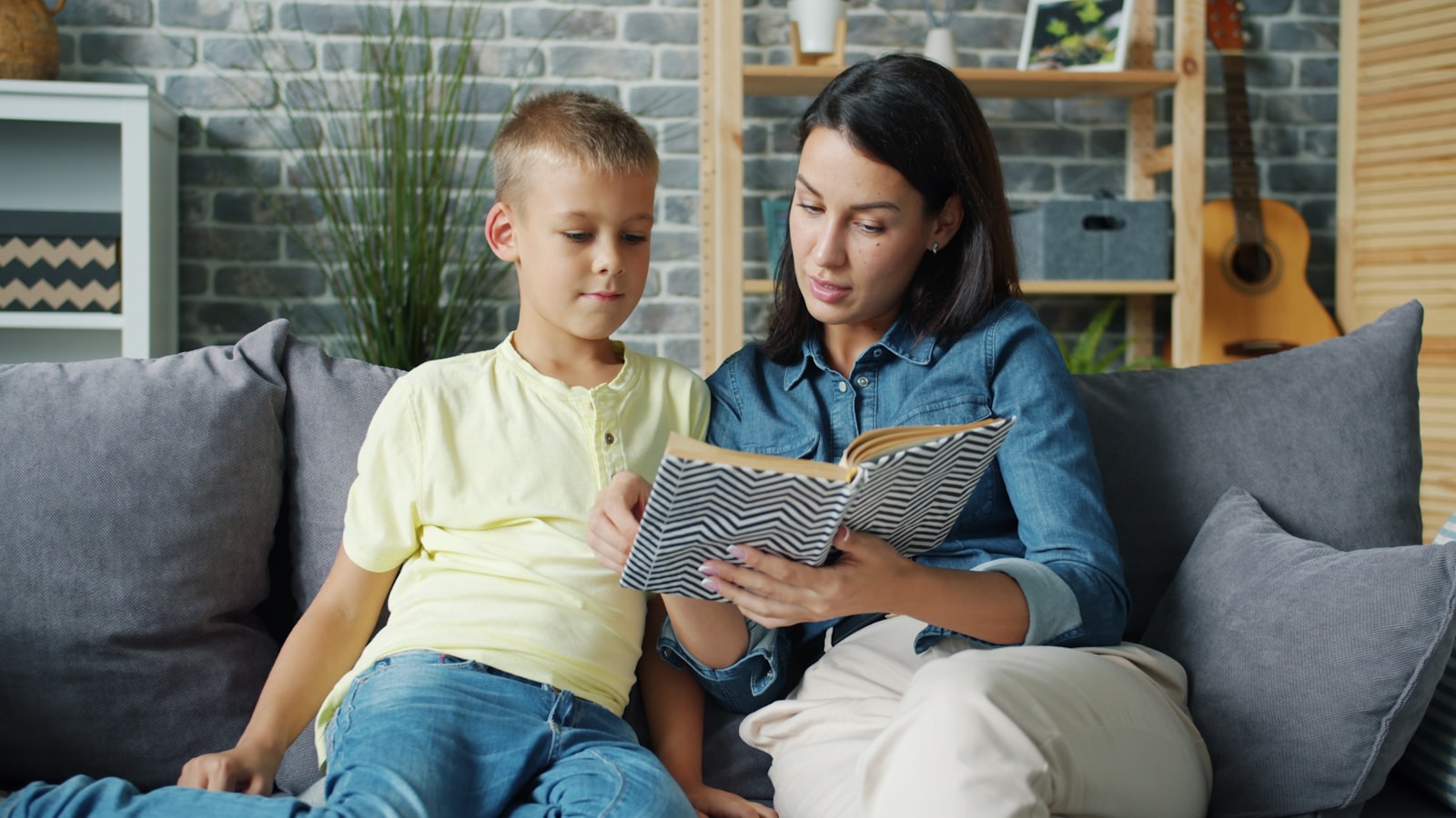 Adulto acompañando a un niño mientras leen juntos un libro